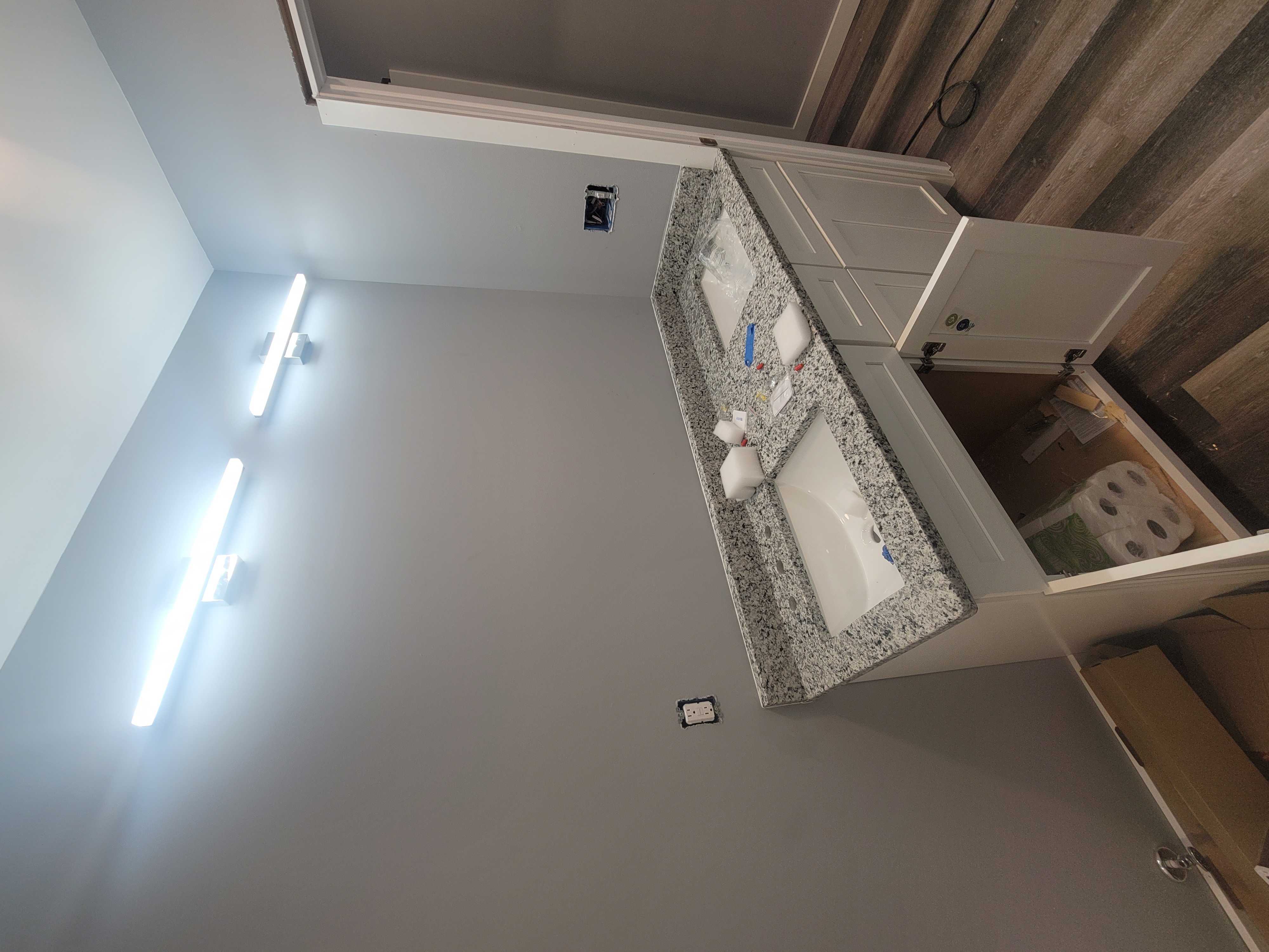 Bathroom with shower, toilet, vanity, and mirror; light blue walls, brown vanity with granite countertop