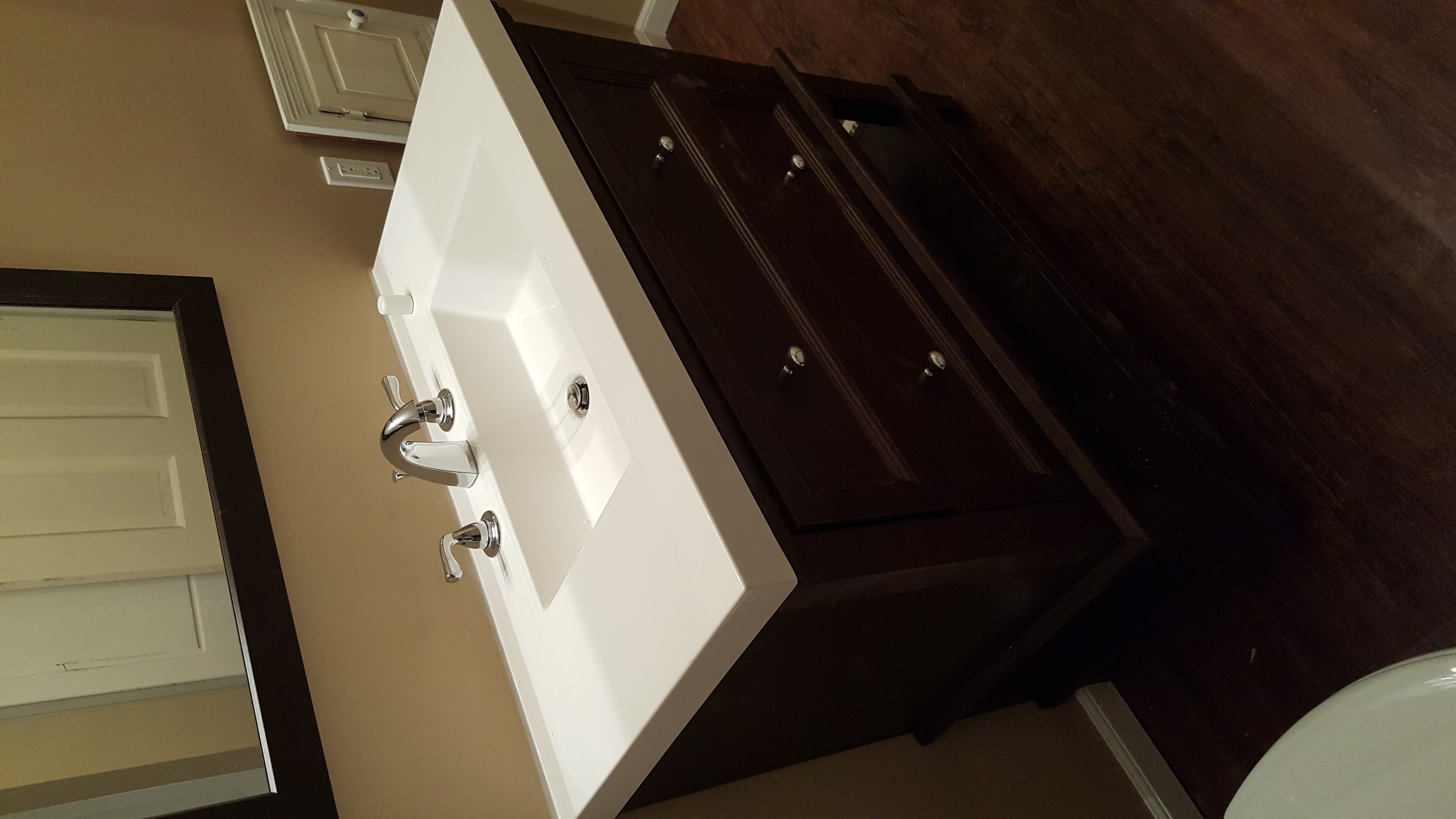 Bathroom with gray walls, white double vanity, granite countertop, and wood-look flooring