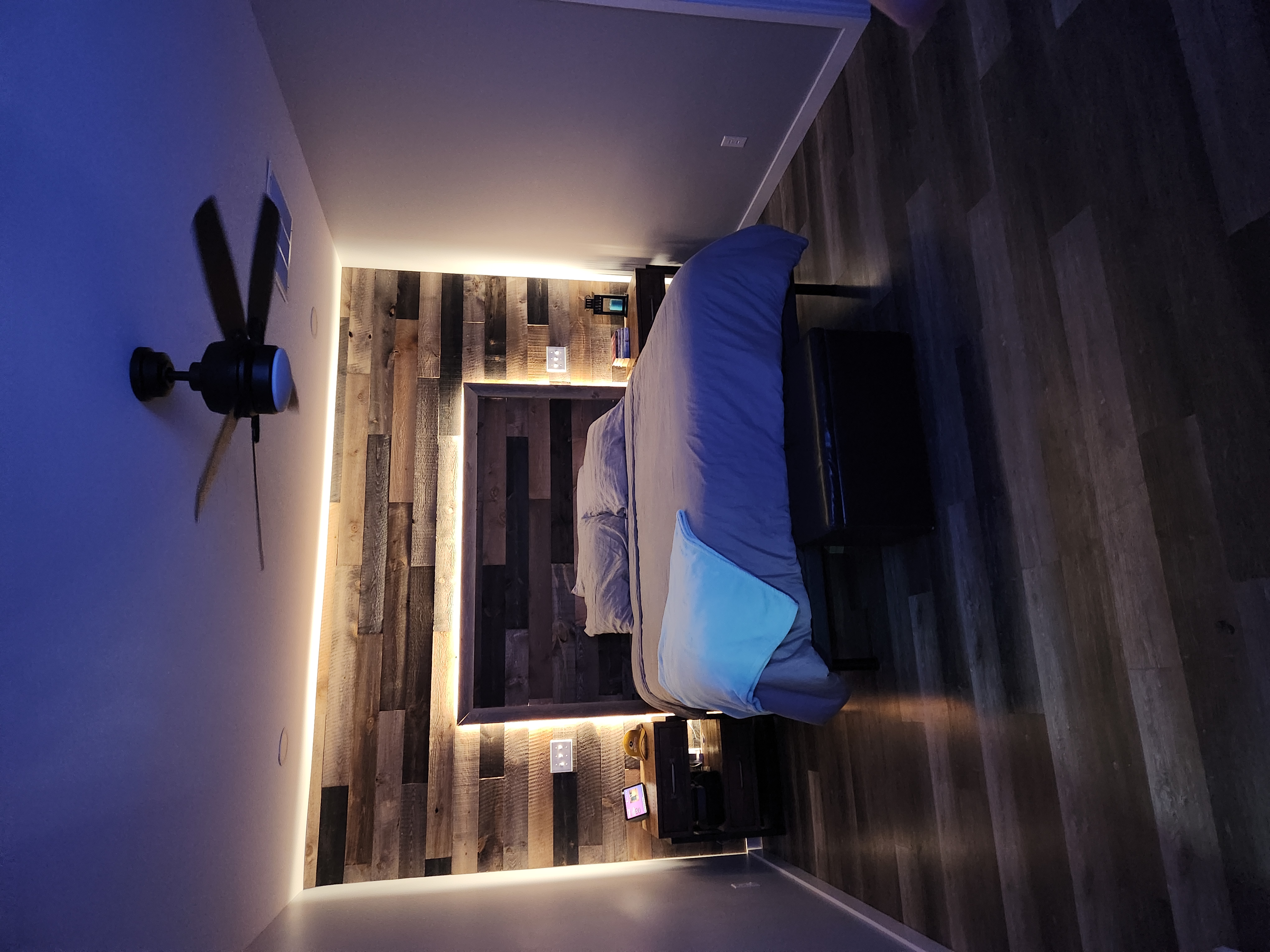 Bedroom with wood accent wall, built-in lighting, bed, and nightstands