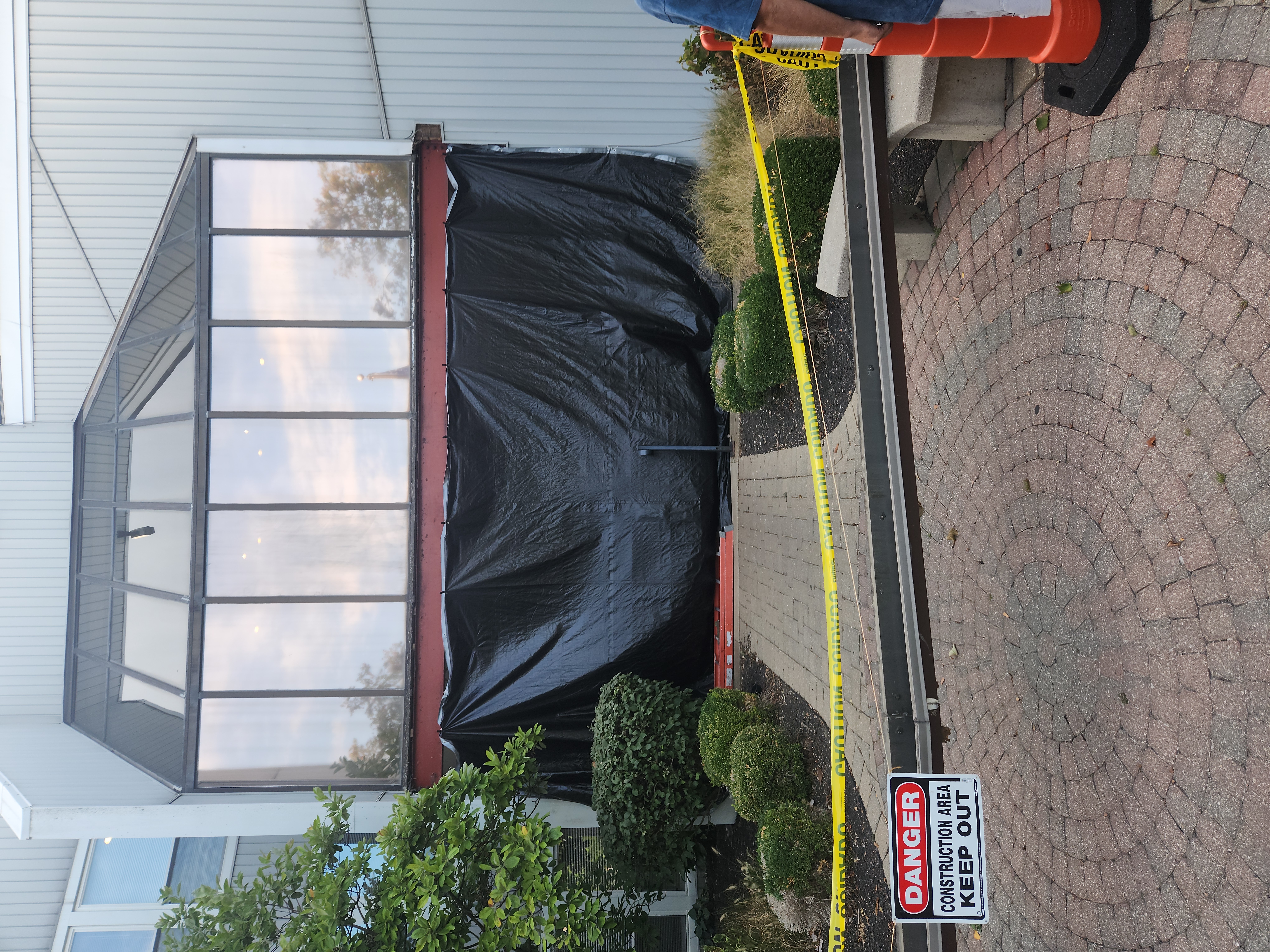 Exterior of a house with windows covered in weather-resistant barrier material; crane in background against blue sky