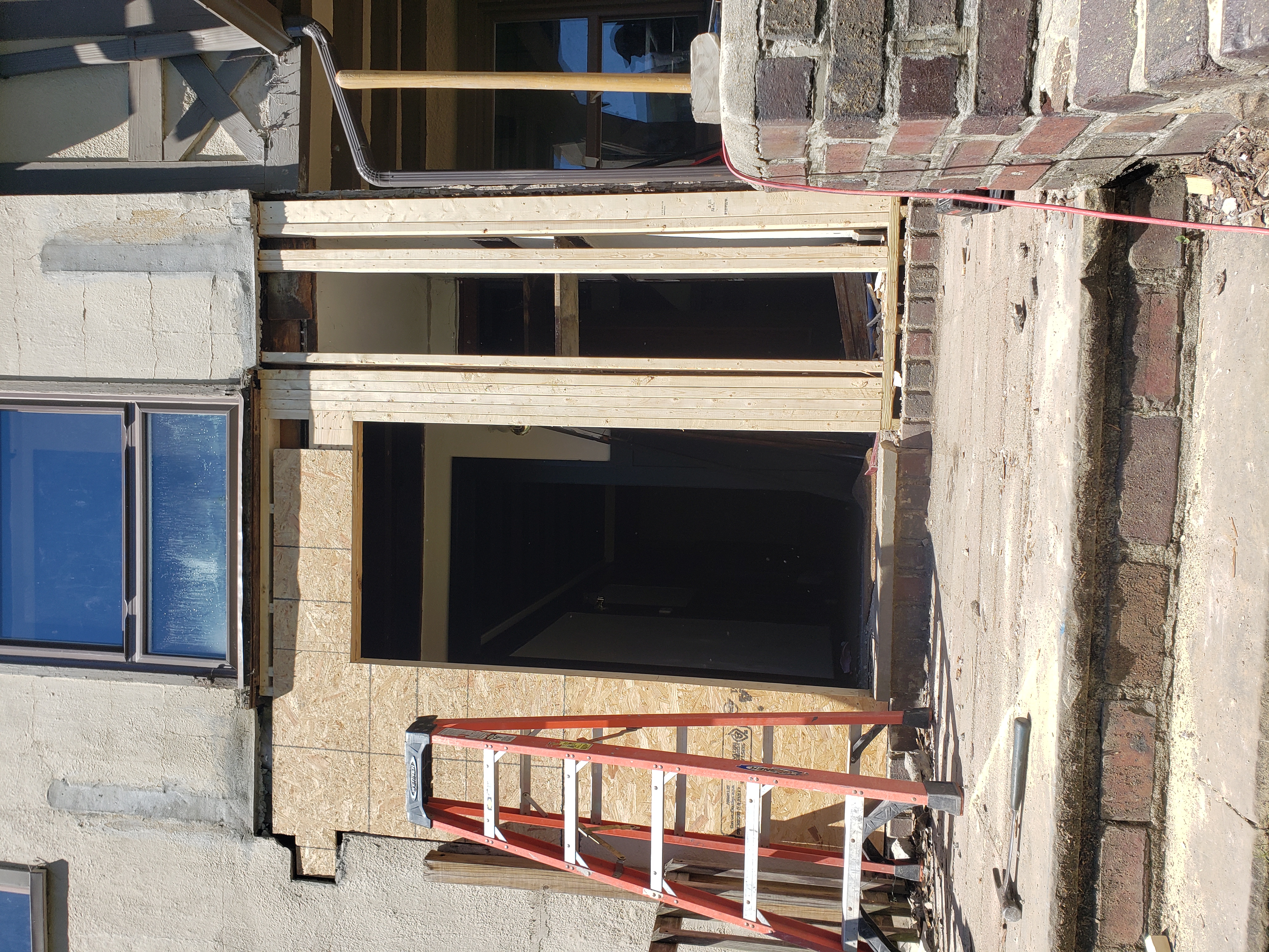 A new brick patio outside a house; an AC unit sits on the patio, steps lead to the back door