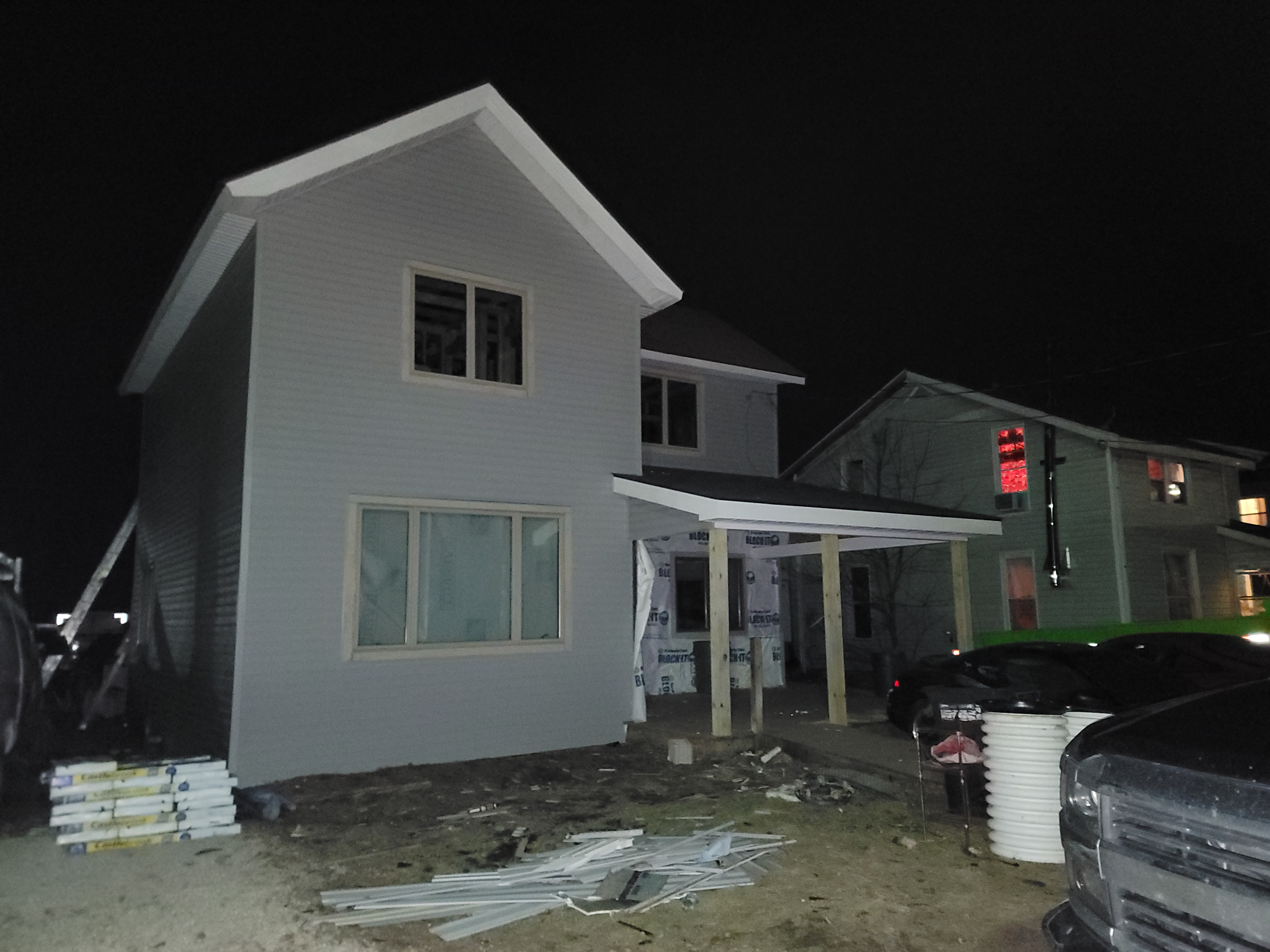 Man on a roof repairing wood panels; black asphalt shingles, outdoors, overcast