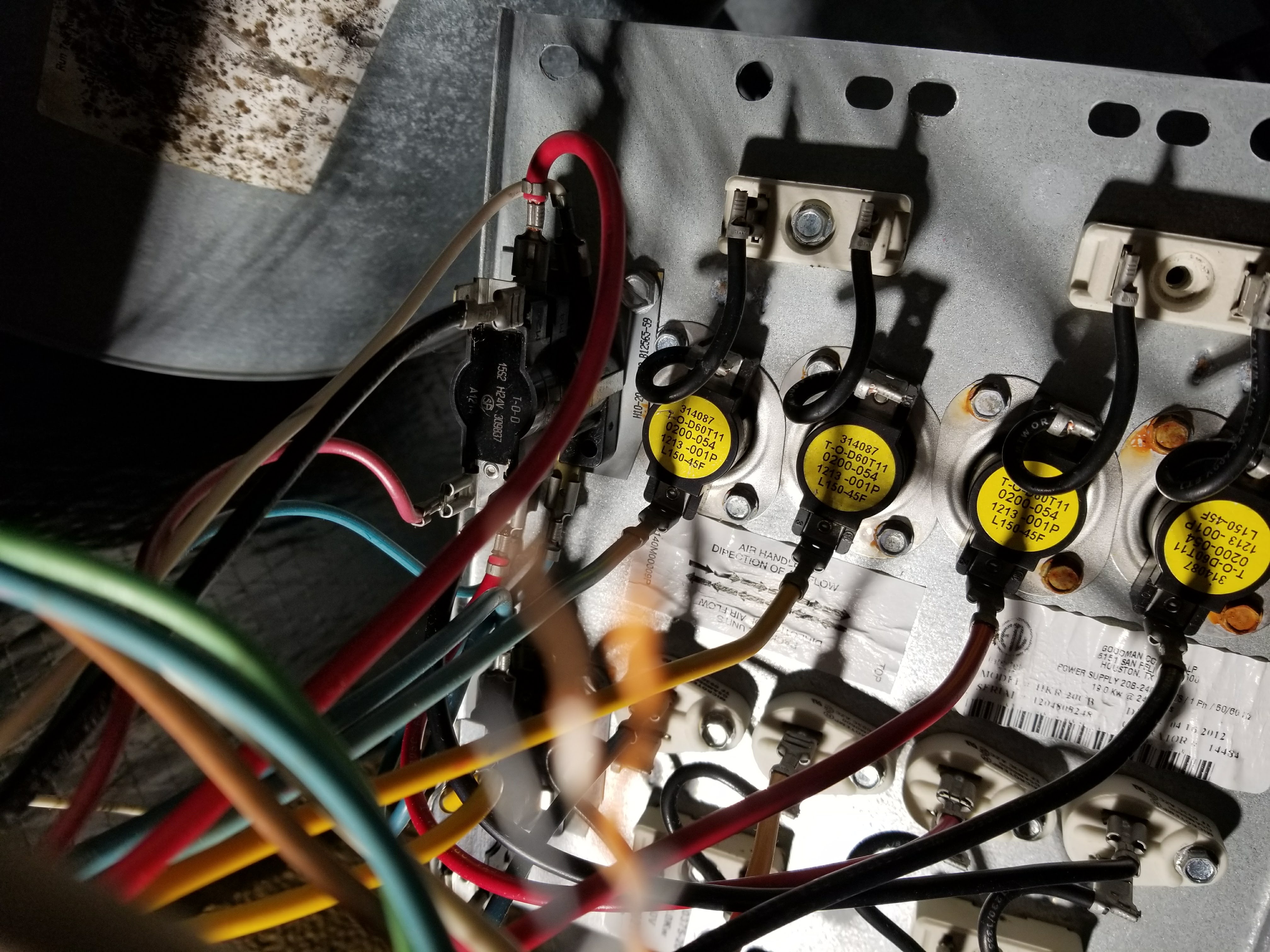 Open electrical boxes mounted on a house exterior, showing wiring and components