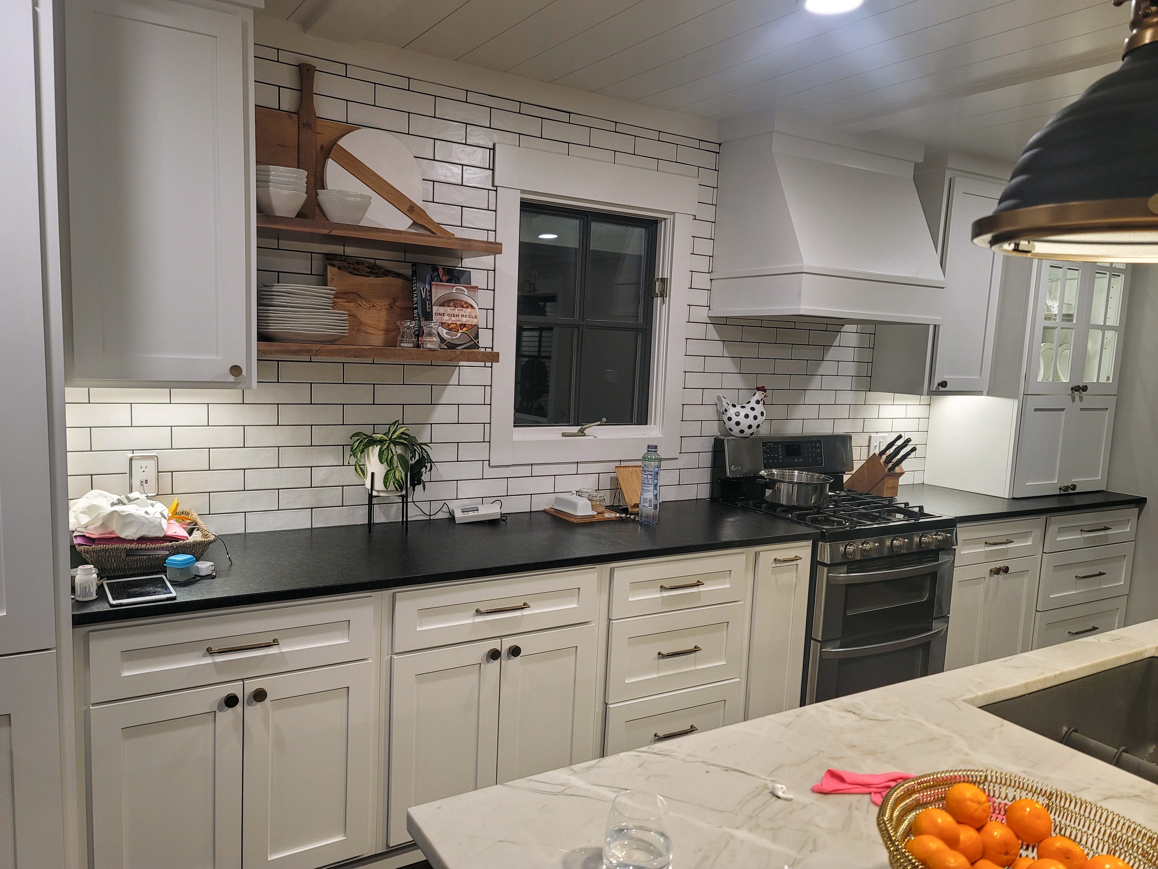 Small office kitchen with white cabinets, stainless steel appliances, table, and colorful chairs