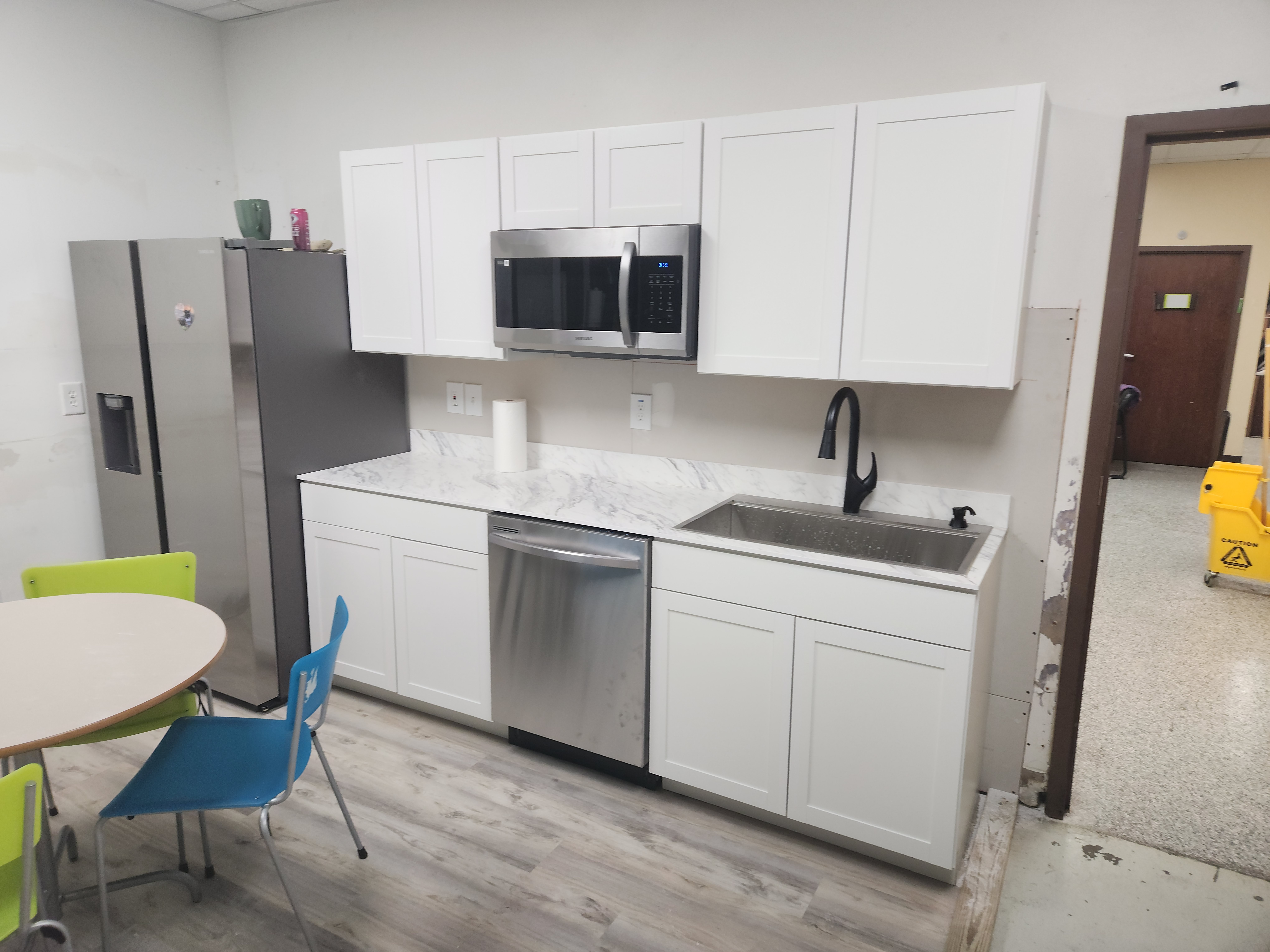 Kitchen renovation before and after: white cabinets, gray countertops, black appliances, and dark backsplash