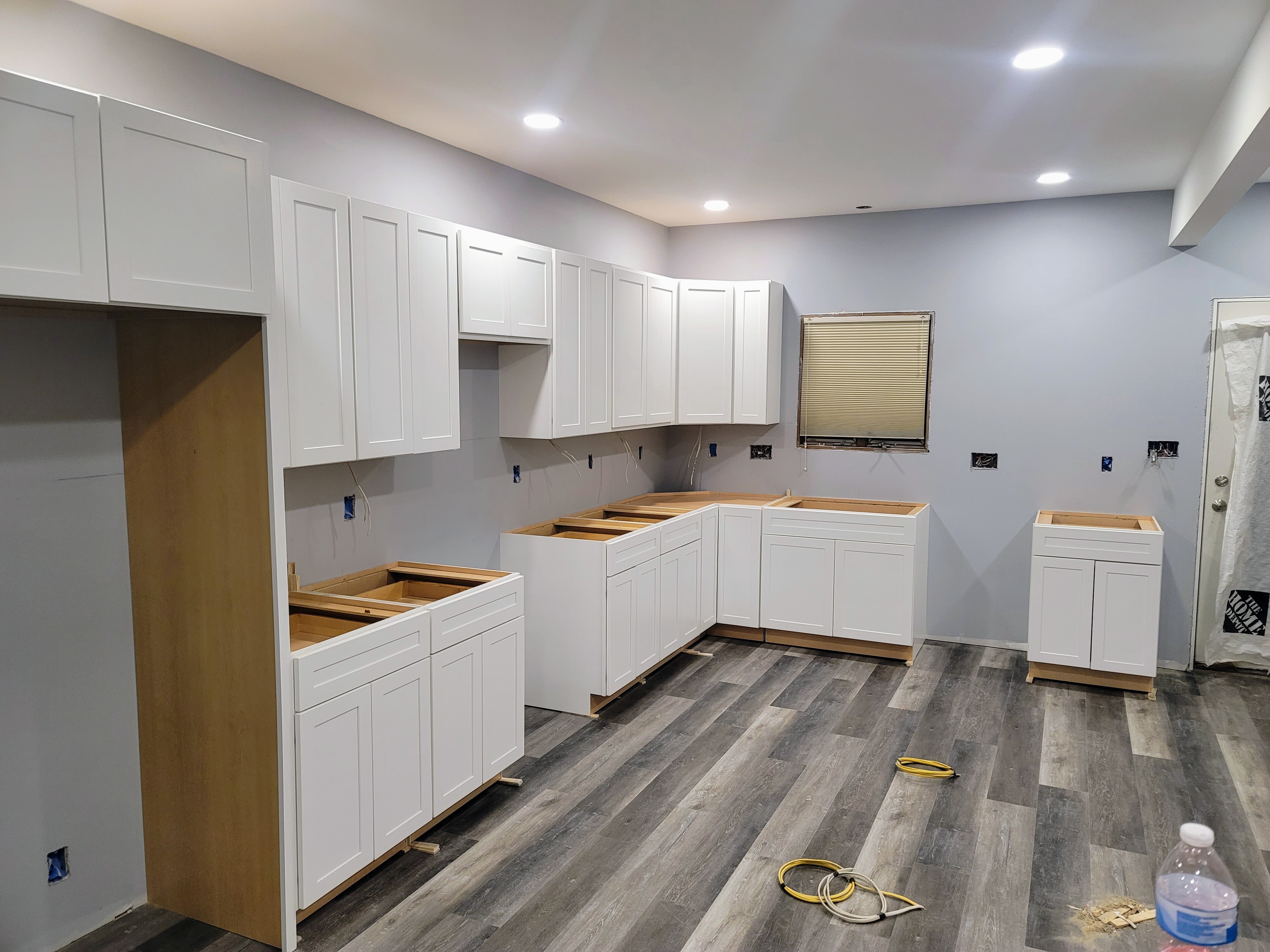 Kitchen area with sink, cabinets, shelves, and a door; gray walls, white cabinets, and neutral decor
