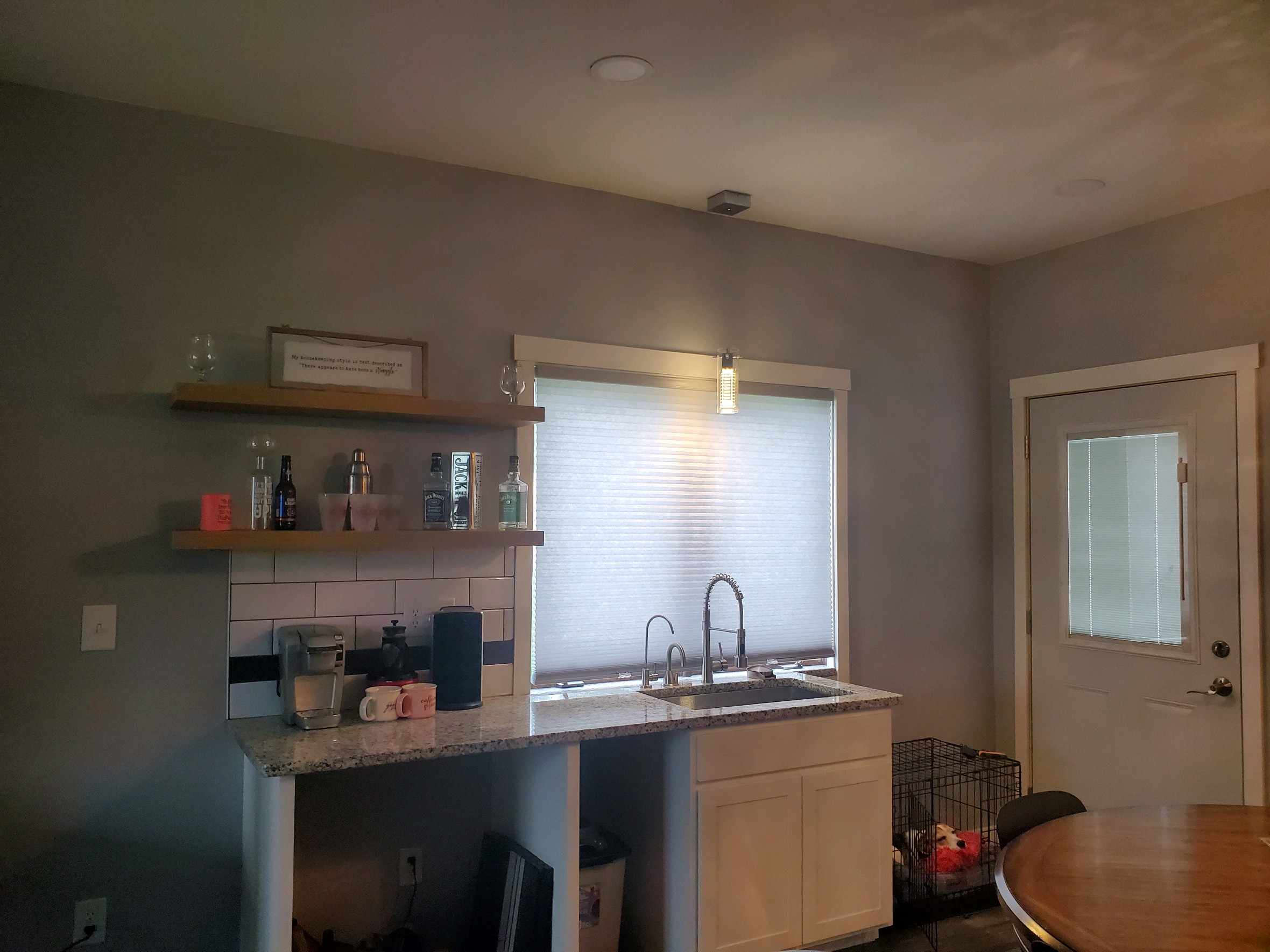 Kitchen with white cabinets, black appliances, and a granite countertop island illuminated by colorful lights